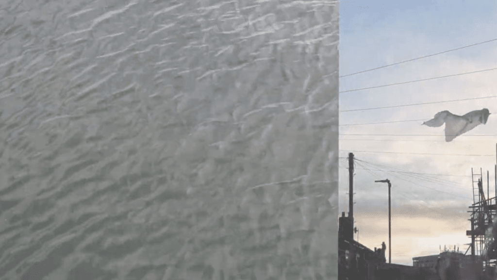 Film still, split screen - grey sea to the left, fabric caught on an urban washing line at sunset on the right